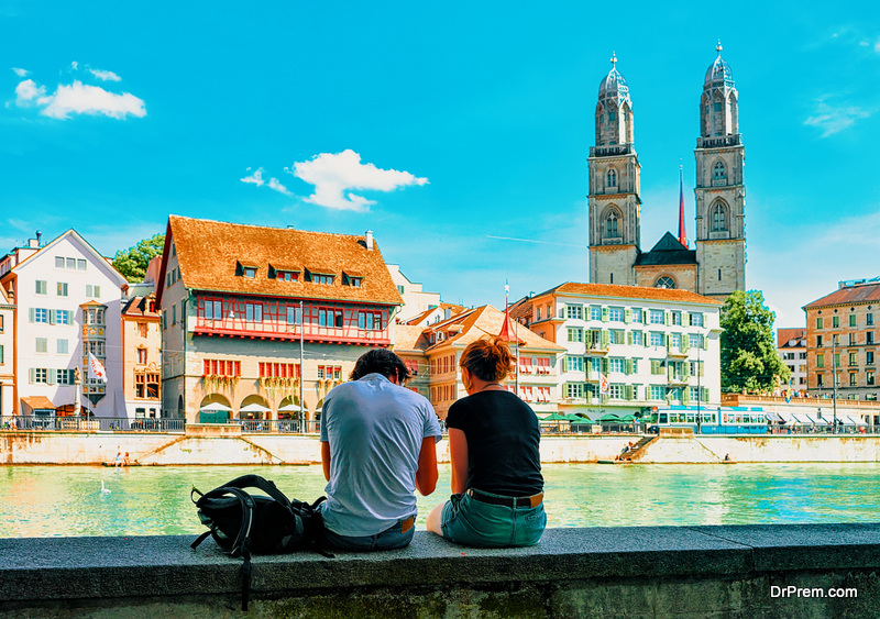 Young couple sitting at Limmatquai Grossmunster Church in Zurich