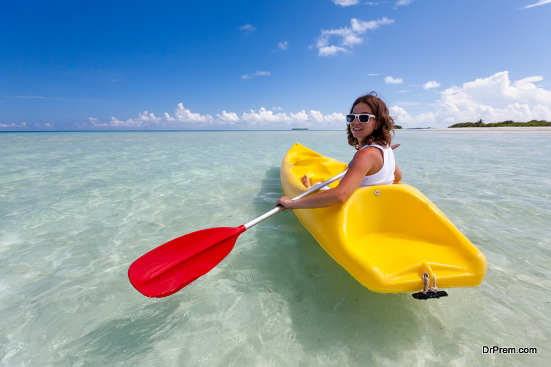 Young caucasian woman kayaking in sea at Maldives